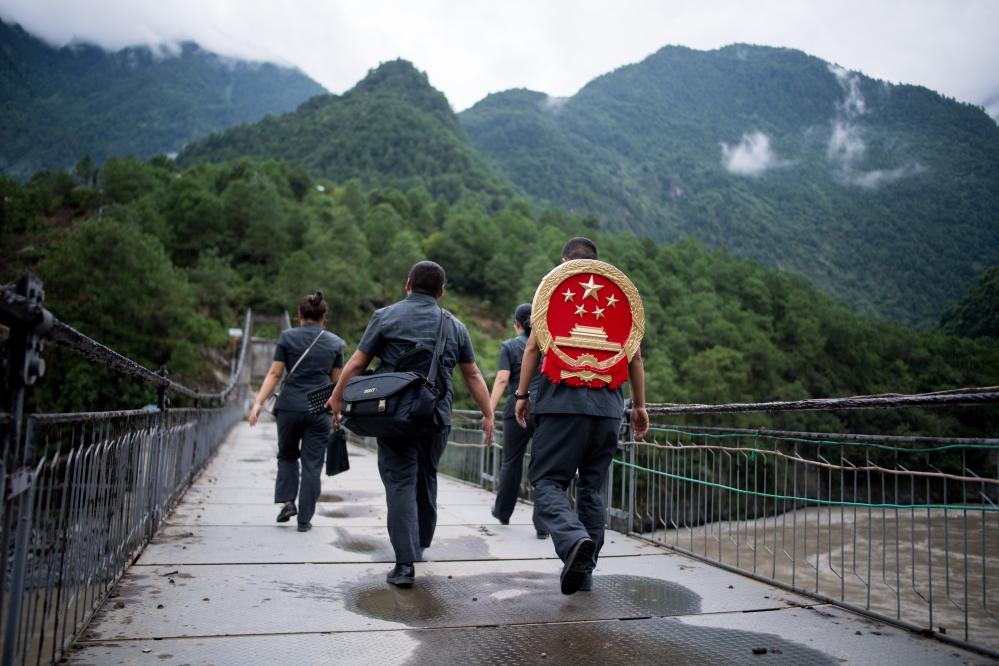云南省怒江傈僳族自治州貢山縣人民法院法官鄧興背著國徽與同事們跨過怒江（2019年8月30日攝）。怒江高山峽谷眾多，交通不便，為方便群眾、更好地開展法律服務(wù)，背著國徽攀高山、過索橋、躲落石、鉆老林……成為鄧興法官的工作常態(tài)。新華社記者 江文耀 攝
