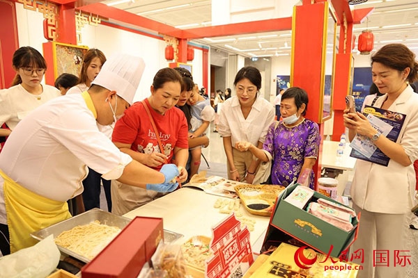 演出前，在天津桂發(fā)祥十八街麻花制作技藝非遺體驗(yàn)展臺前，泰國民眾體驗(yàn)天津麻花制作。人民網(wǎng)記者 楊一攝