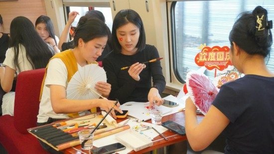 10月1日，旅客們在G1634次列車上給油紙傘作畫。新華社記者周義 攝