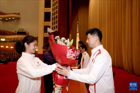 11月15日，一名學(xué)生代表在報(bào)告會(huì)上向乒乓球運(yùn)動(dòng)員馬龍（右）獻(xiàn)花。新華社記者 李明 攝