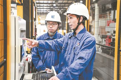 在廣西柳工機械股份有限公司生產(chǎn)車間內，一名高級技師（右）給徒弟講解數(shù)控設備操作細節(jié)。新華社記者 曹祎銘攝