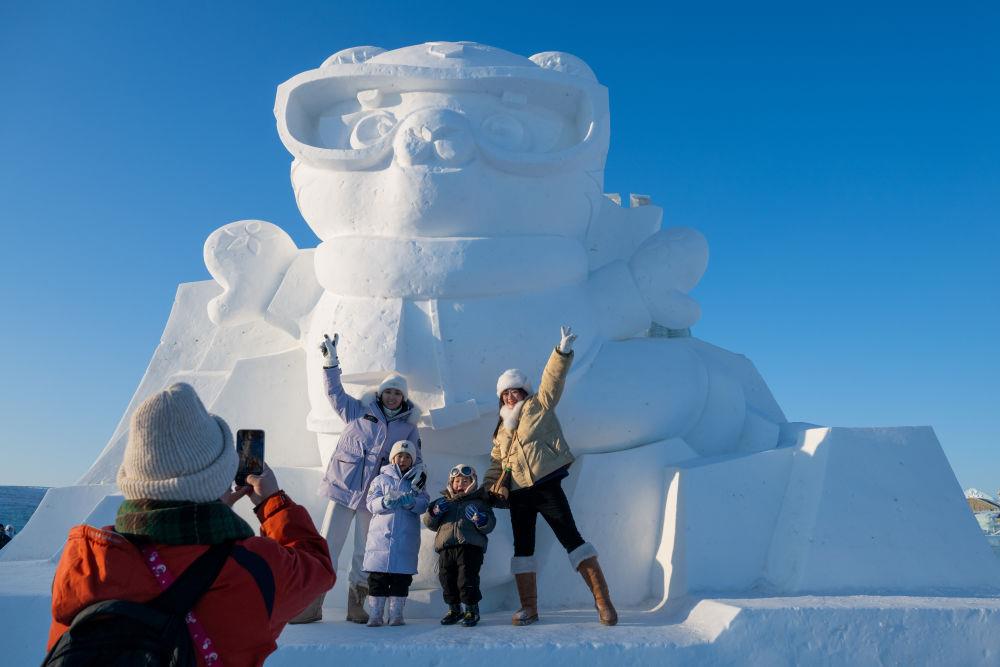 2025年1月3日，在黑龍江哈爾濱冰雪大世界園區(qū)，游客與亞冬會(huì)吉祥物雪雕“濱濱”合影