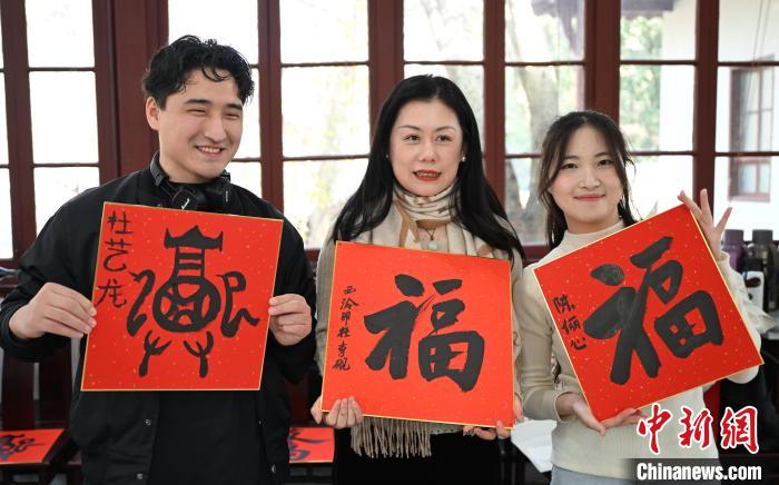 1月20日，外籍留學(xué)生和西泠印社社員李硯(中)展示各自創(chuàng)作的福貼。當(dāng)日，來(lái)自巴西、馬來(lái)西亞、加納、哈薩克斯坦的外籍留學(xué)生在浙江杭州西泠印社體驗(yàn)福貼、春聯(lián)和篆刻，感受古老的中國(guó)傳統(tǒng)文化。中新社記者 王剛 攝