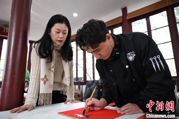 1月20日，外籍留學(xué)生在西泠印社社員李硯指導(dǎo)下寫福。當(dāng)日，來(lái)自巴西、馬來(lái)西亞、加納、哈薩克斯坦的外籍留學(xué)生在浙江杭州西泠印社體驗(yàn)福貼、春聯(lián)和篆刻，感受古老的中國(guó)傳統(tǒng)文化。中新社記者 王剛 攝