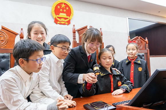 圖①：干警帶同學(xué)們體驗(yàn)敲法槌。