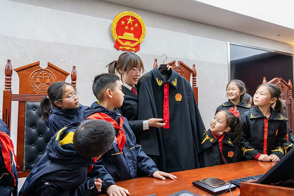 圖②：干警向同學(xué)們介紹法袍。