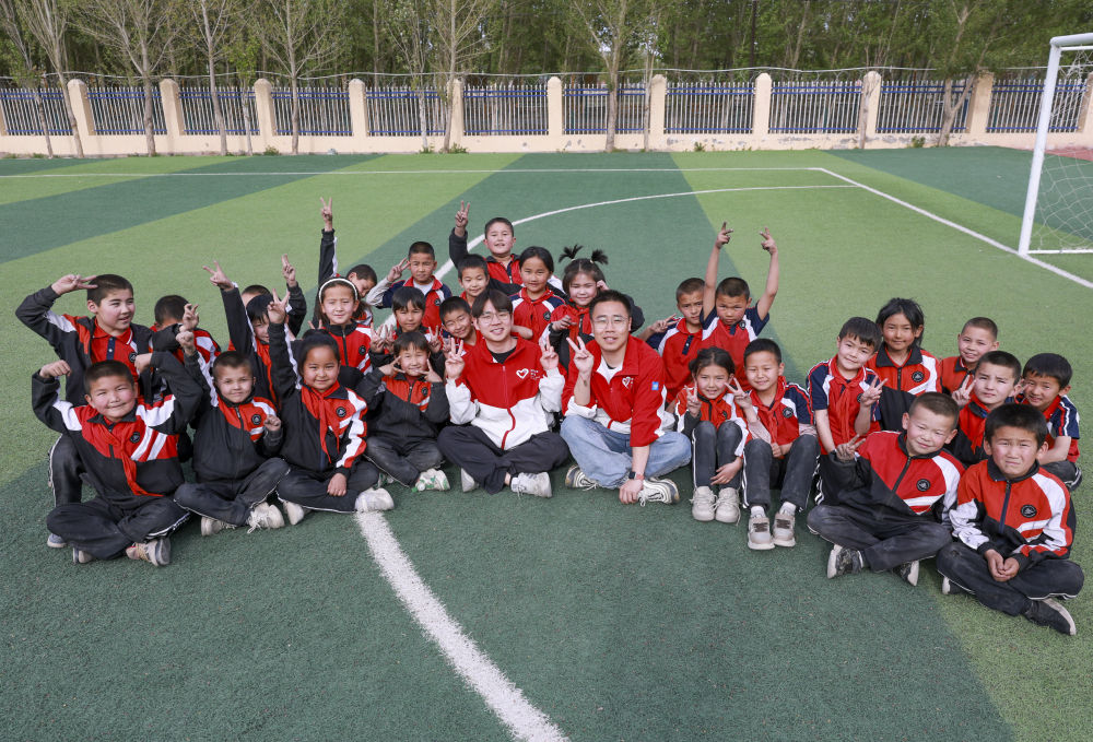 4月23日，在新疆克州阿圖什市哈拉峻鄉(xiāng)謝依特小學(xué)，支教教師王俊文（中左）、李軻凡（中右）和學(xué)生在一起。